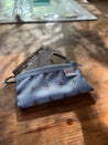 A small blue trail Wallet with keys, a credit card and 5 dollar bill from a 45 degree angle