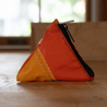 A small pyramid shaped pouch made from orange upcycled sailboat sail