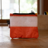 A small orange and white rectangle pouch made from upcycled sailboat sail