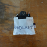 A small white rectangle pouch made from upcycled sailboat sail with the zipper open reveling a headlamp inside