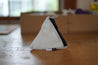A Small pyramid shaped pouch made from white upcycled sailboat sail - sitting on a table